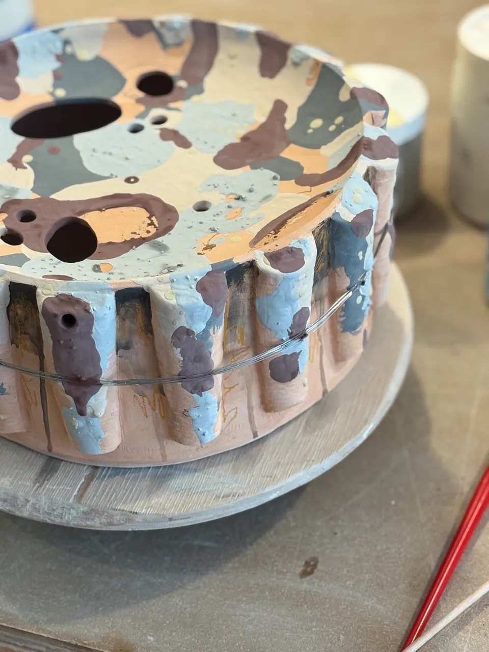 A fluted vessel on the wheel, dripping with slip, waiting to be trimmed.