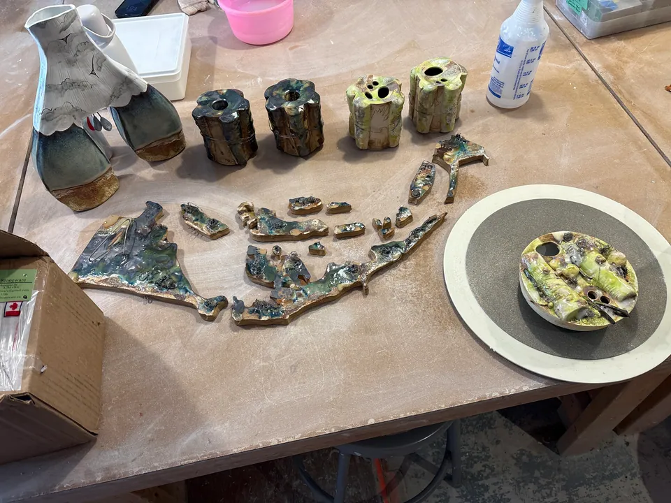 A studio table with finished pieces and a bowl of glaze laid out.