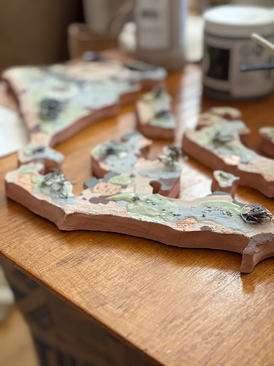 A shard-shaped piece on the bench being painted with a fine brush.