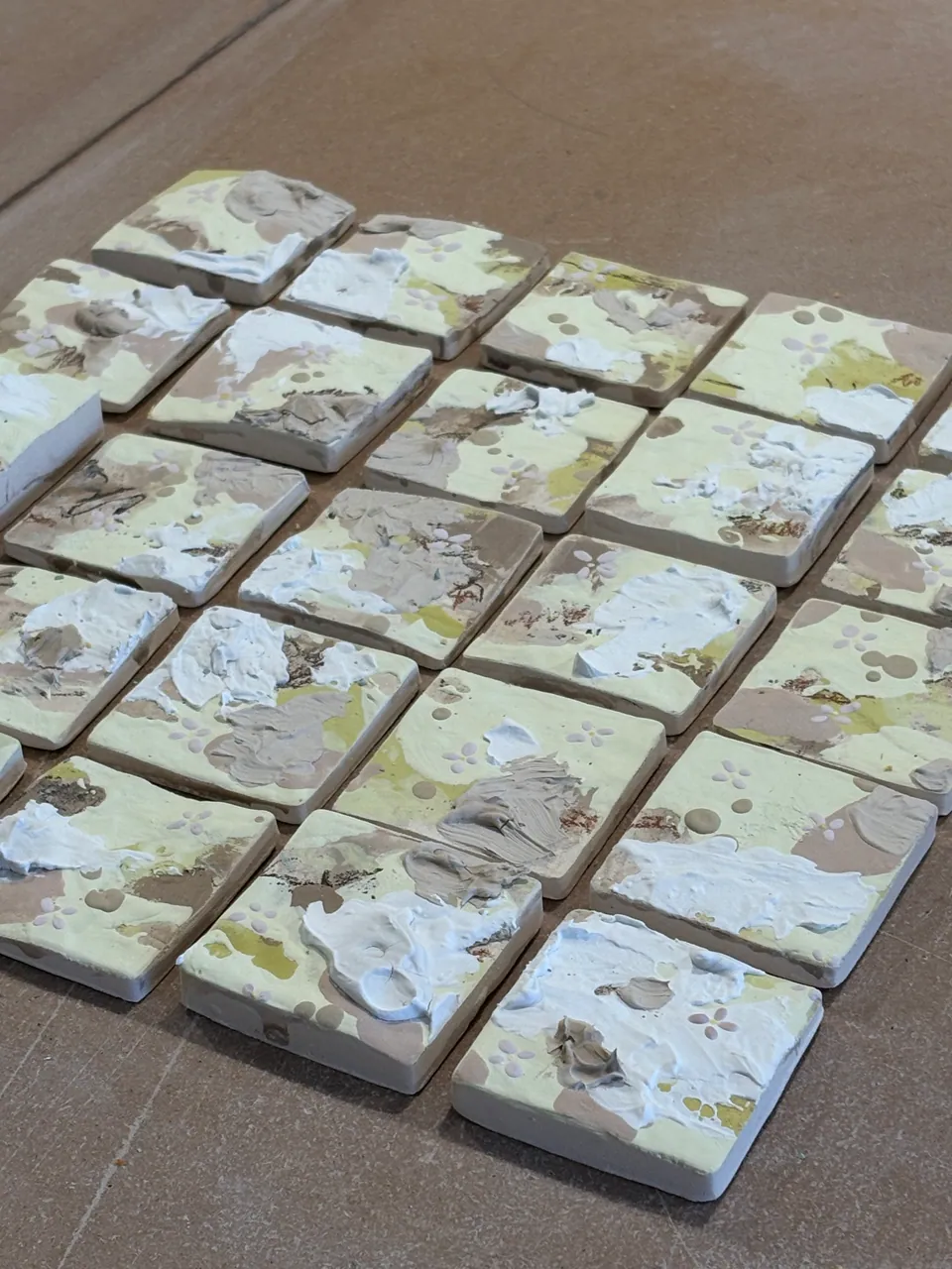 A grid of small glazed tiles laid out on a board.