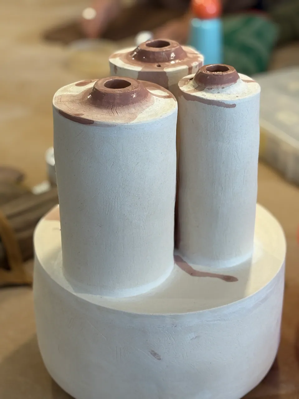 Two white stoneware cylinders standing on a plaster bat.